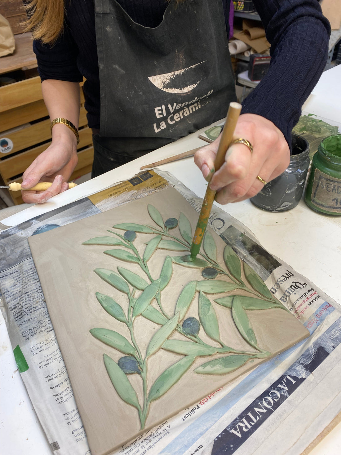 La clara pintant la seva obra, unes fulles d'olivera en volum